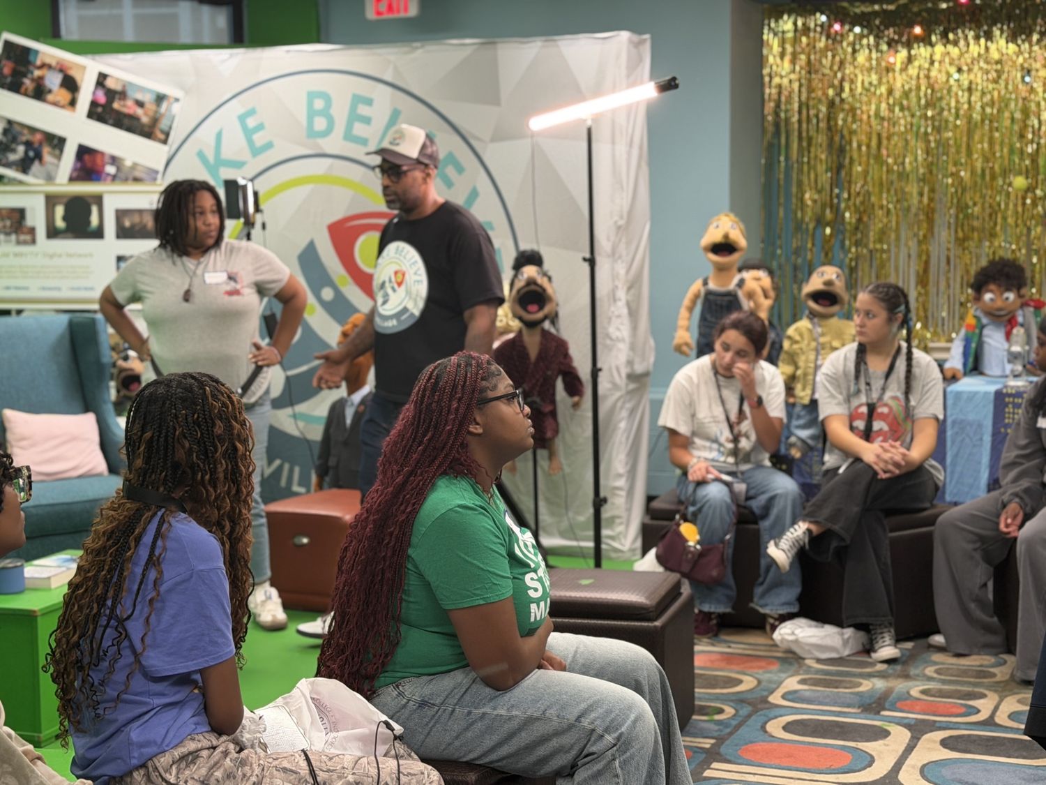 Students and mentors gathered in the Make Believe Village lounge, the puppet cast on stands behind them.