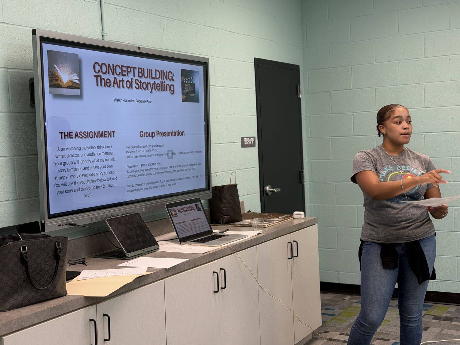 A student presenting to the room in front of a slide reading Concept Building: The Art of Storytelling.
